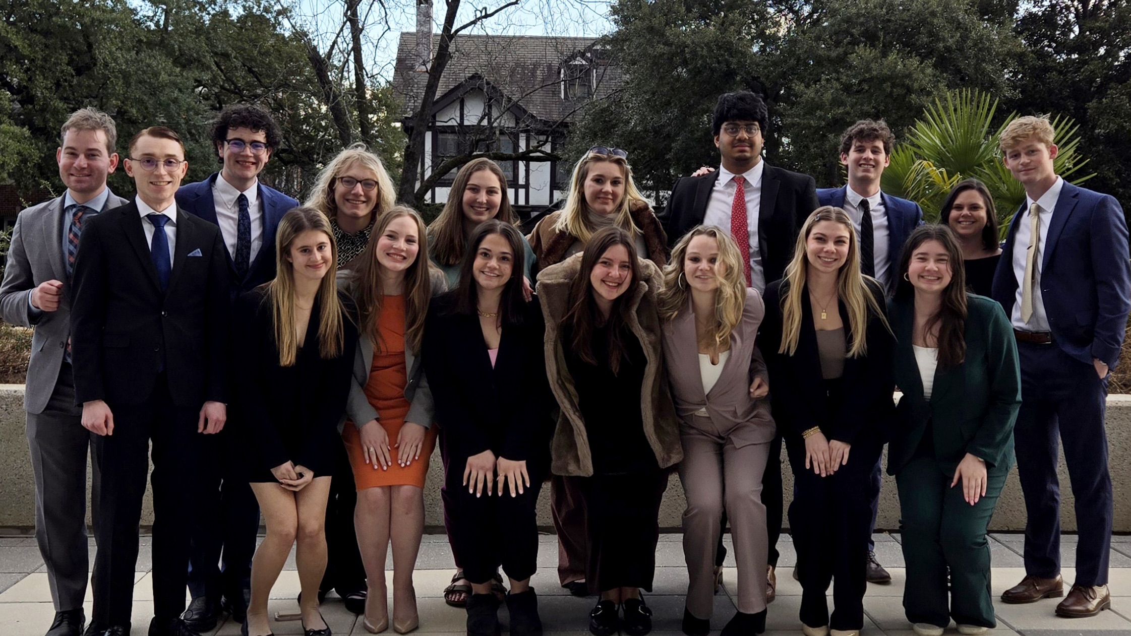 a group of students in suits and dresses posed for a group photo