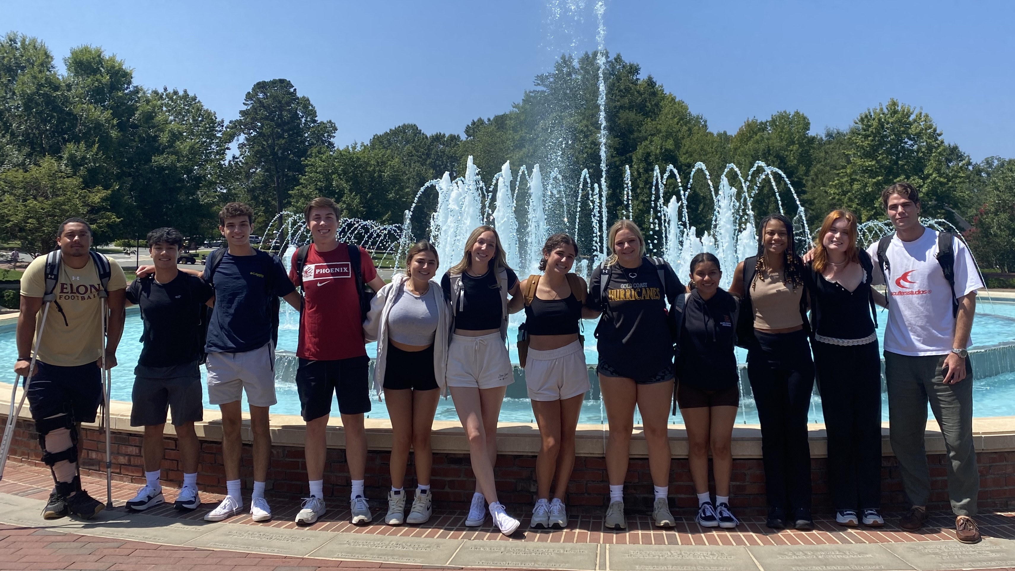 A group of students posed in a line in front of the fountain at Koury Business Center