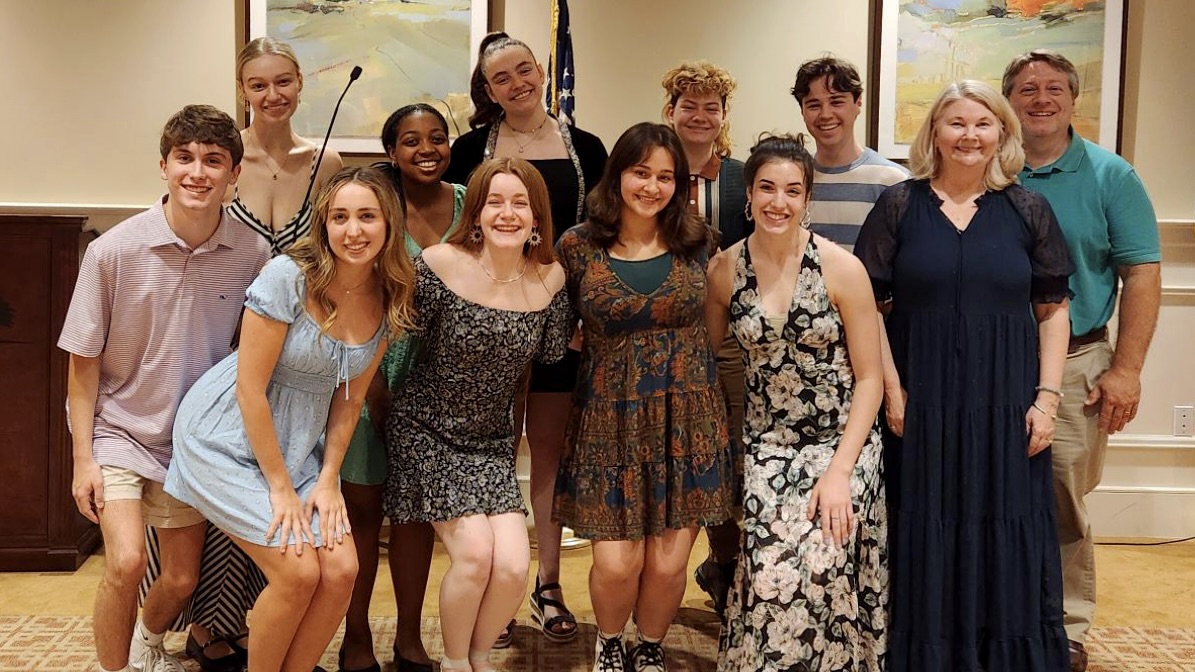 a group of students and two instructors posed for a photo inside a gathering space