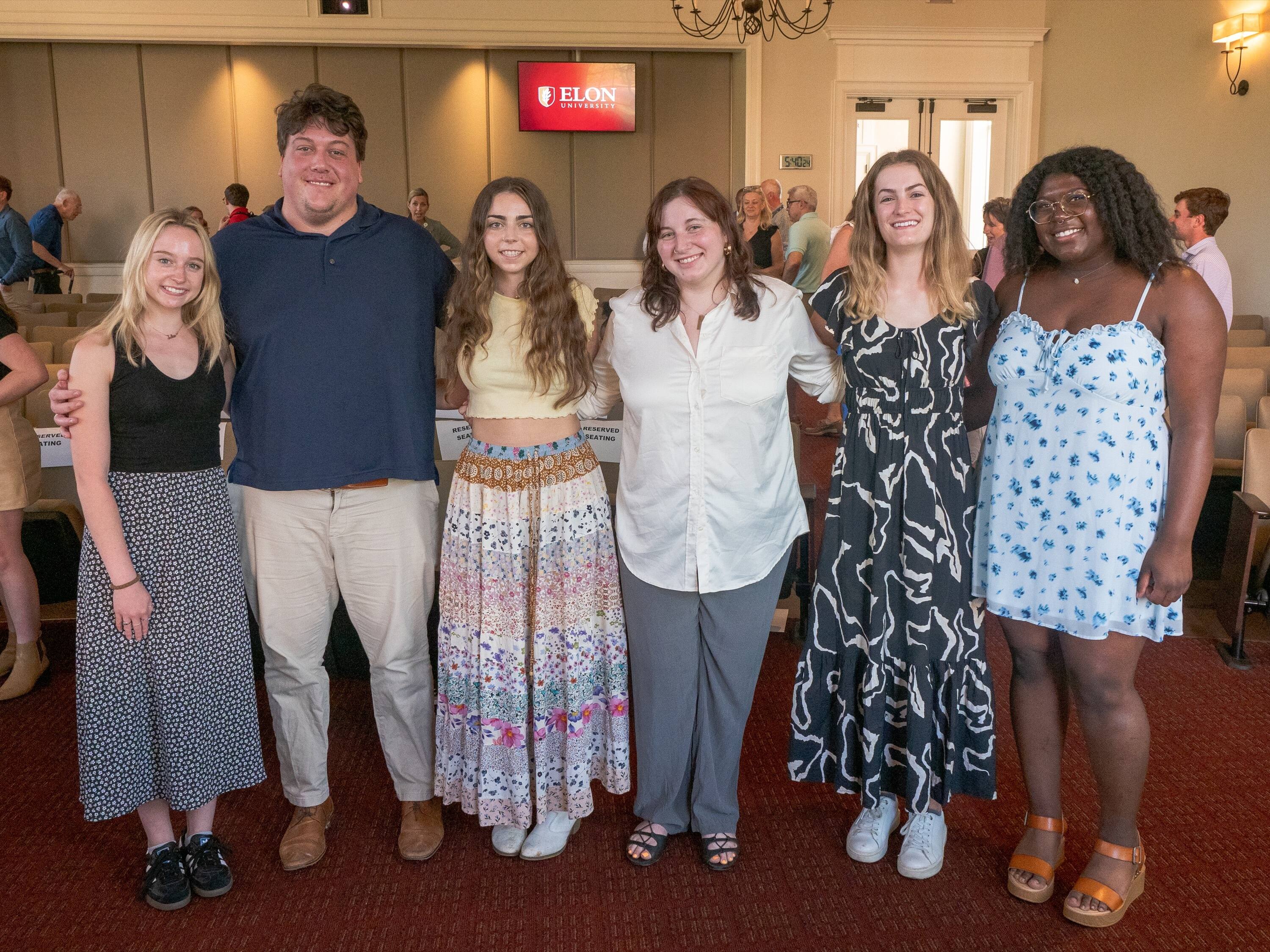 Julia Burpeau, Mollie Lund, Nicole McGinty, Nyjah Rollins, Nolan Schreiner and Frieda Walsh pose for a photo in a large hall