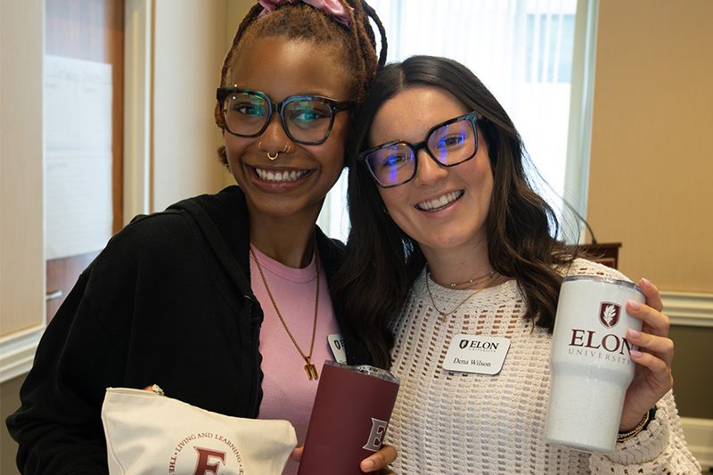 two Elon MHE students holding up Elon cups