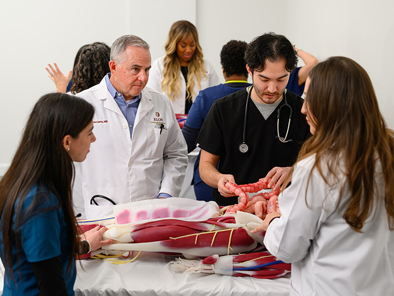 Elon PA in Charlotte faculty and staff learning on a mannequin for PA program