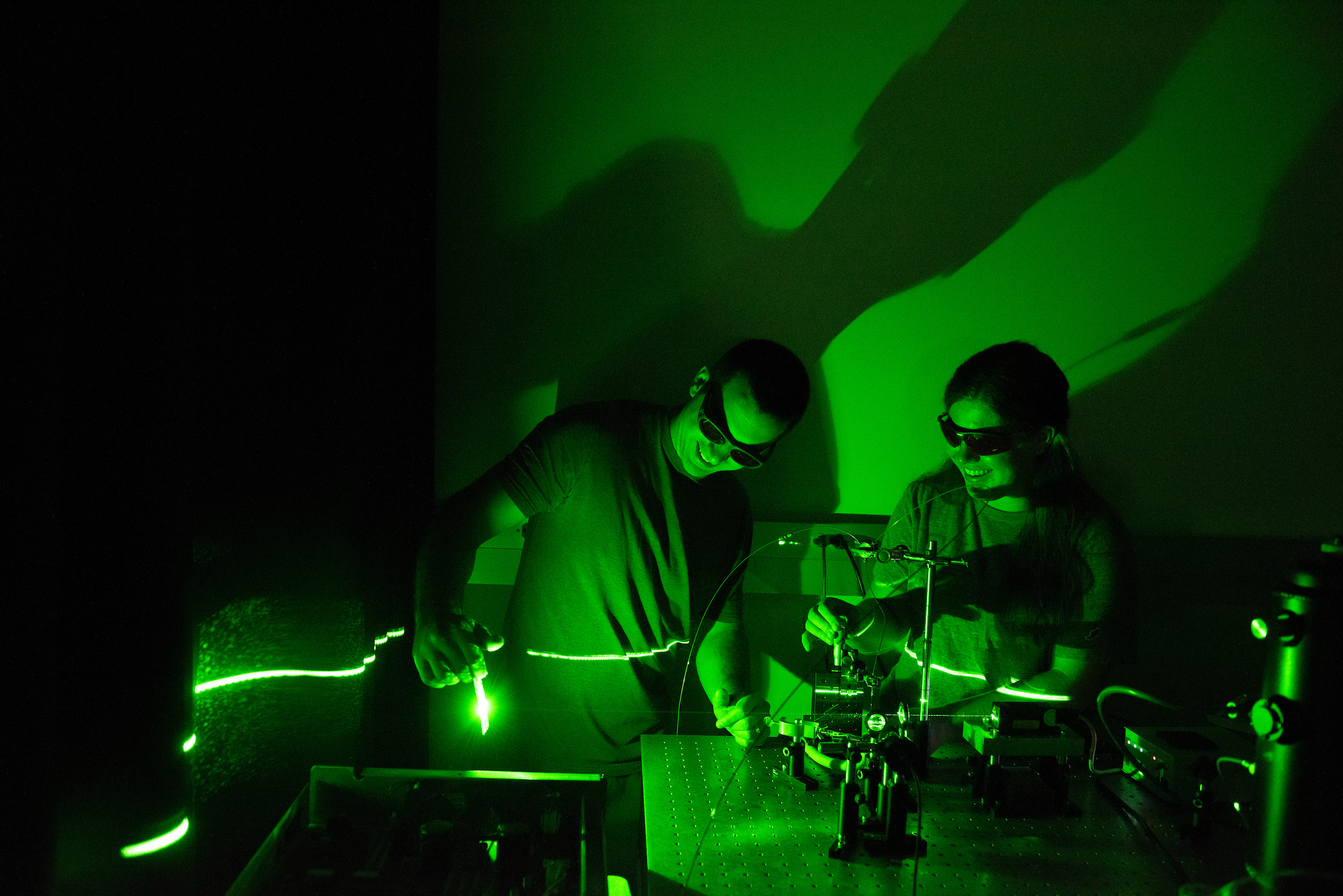 A professor and student in a laser lab shown in green light. Explore a degree in biochemistry at Elon University.