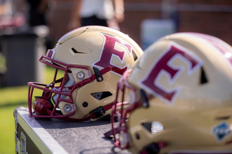 Photo of two Elon football helmets sitting on a bench