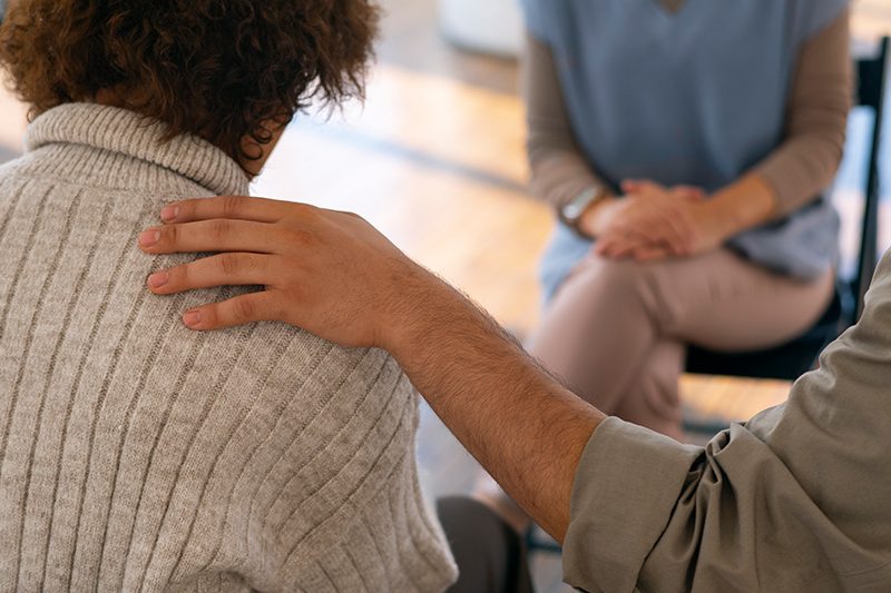 A clinical mental health counselor comforting someone in need with hand on shoulder