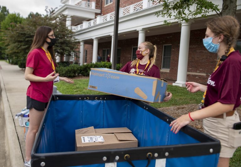 Elon students wearing masks help move boxes into a residence hall during new student move-in.