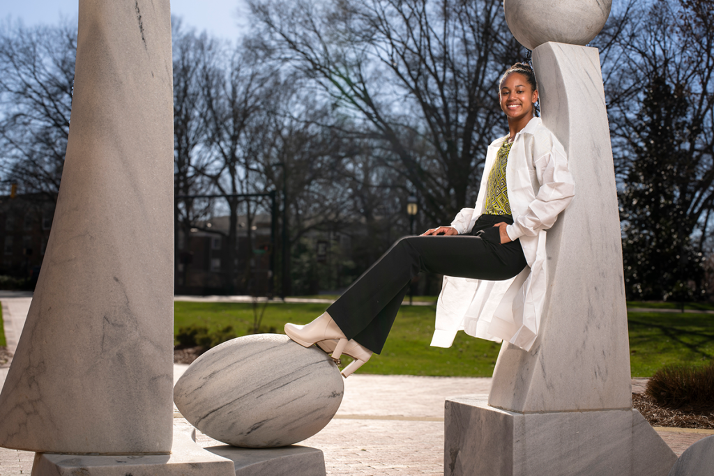 African American women in a white coat sitting on a sculpture