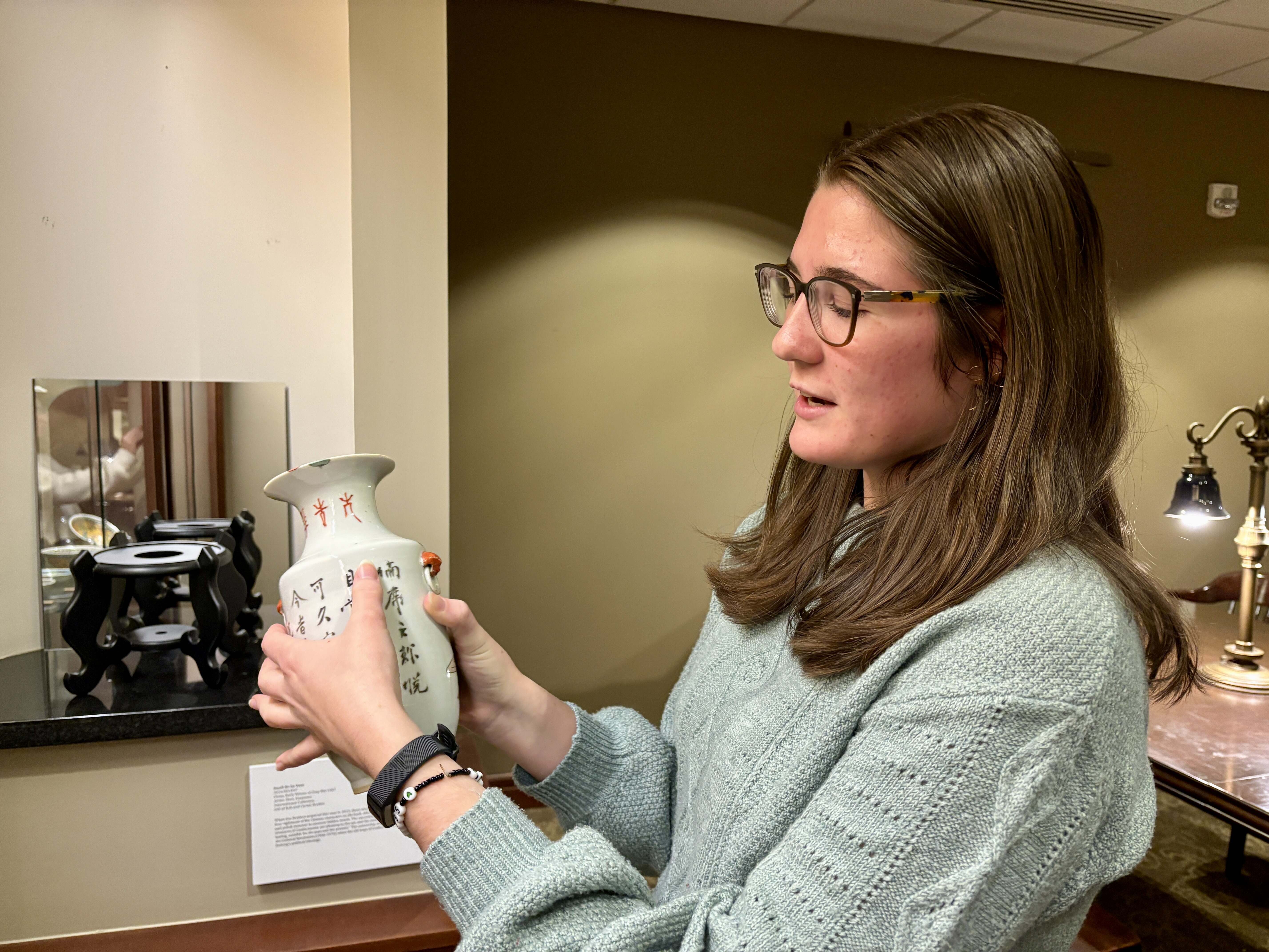 Lizzie Ostling '26, a student worker with the Arts Collection, holding a piece of porcelain art