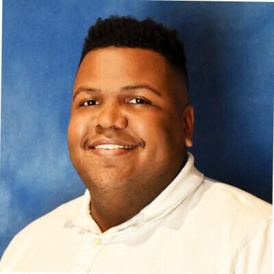 African American man wearing a white polo.