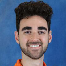 Man with brown hair, a beard and wearing an orange shirt.