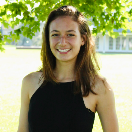 Charlotte is wearing a black dress and she is standing up and posing.