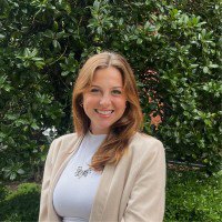 Lillian Argabrite posing for a photo. She has brown hair and is wearing a white shirt with a cream colored cardigan.