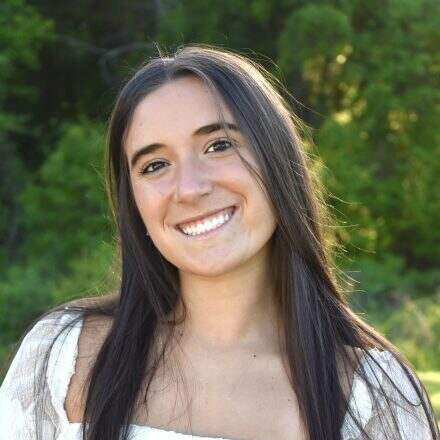 Woman with straight brown hair and a white shirt.
