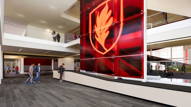 Architectural rendering of the Slattery Center atrium featuring a large illuminated Elon Phoenix logo on a red wall, with multi-level open spaces and a fitness area visible.