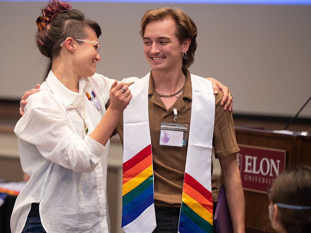 PHoto of a graduate receiving a rainbow stole during Elon University's Lavender Graduation ceremony