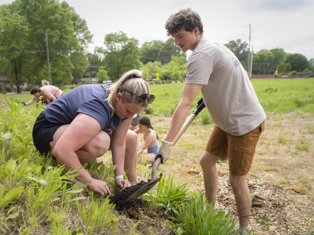Photo of two students planting vegetation together at the Eco Village