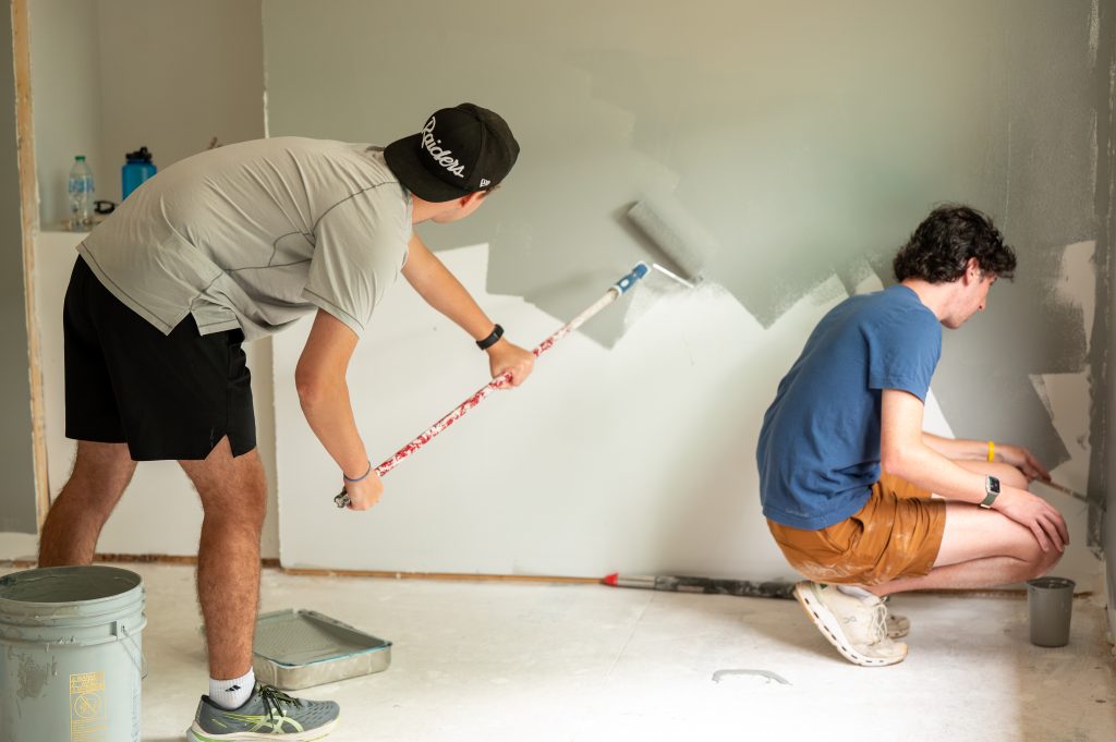 Photo of volunteers rolling gray paint onto walls during a Habitat for Humanity build