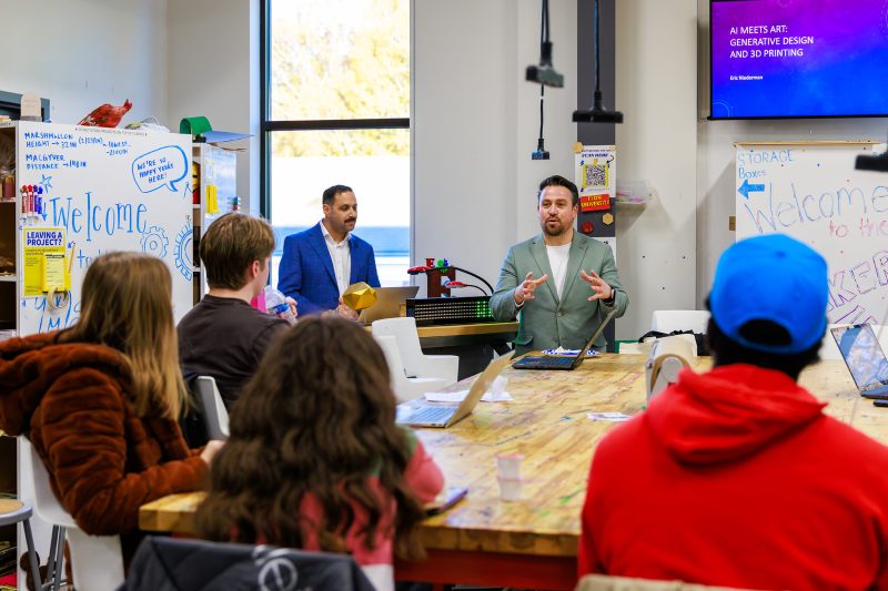 Mustafa Akben and presenter Eric Niederman speaking to students in the Elon University Maker Hub during an "AI Meets Art: Generative Design and 3D Printing" session.