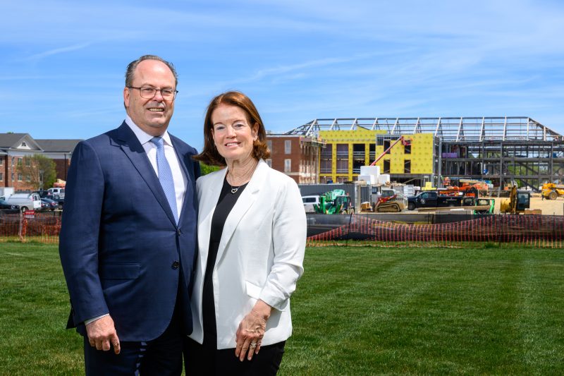Bill and Tish Slattery posing in front of the Slattery Center under construction at Elon University