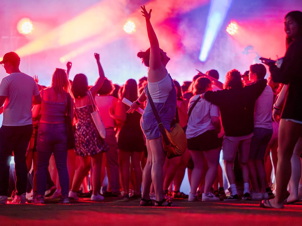 Photo of seniors dancing under colorful lights during Senior Celebration on campus