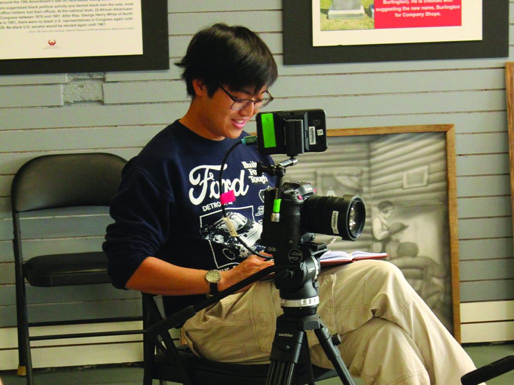Student Aaron Chan '26 sitting behind a video camera and conducting an interview for a documentary film