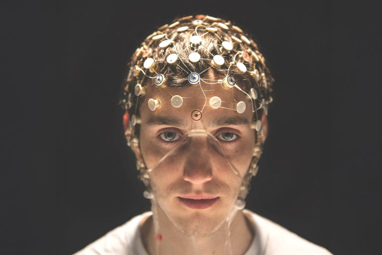 a person with a net of sensors covering his head takes part in a neuroscience experiment