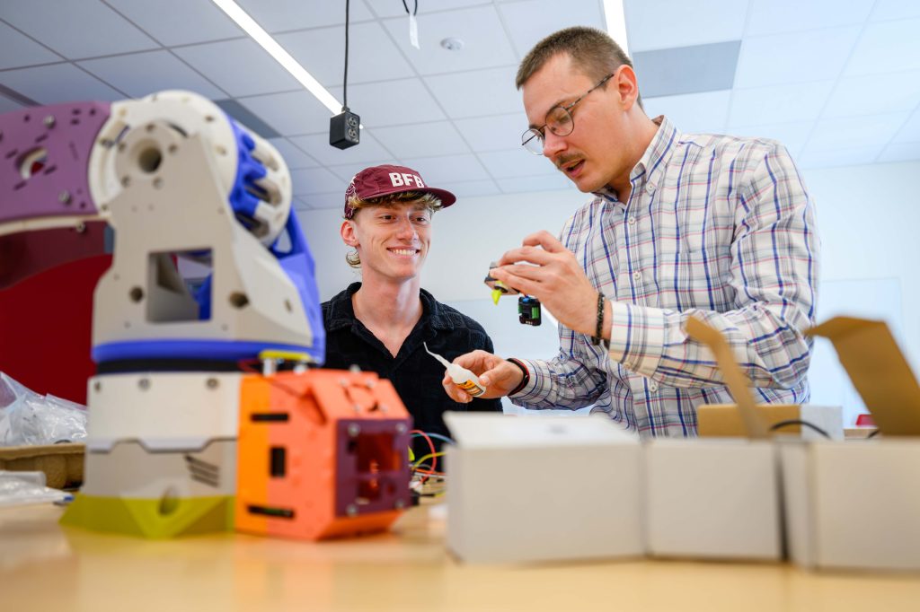 A professor and student work with robotics equipment