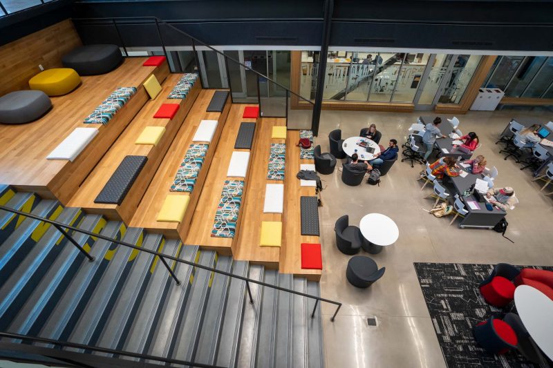 View from above looking down onto students seated around tables in a large hall
