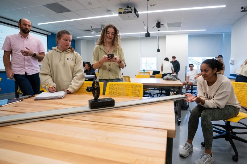 Students run an experiment with a fan-propelled device on a track