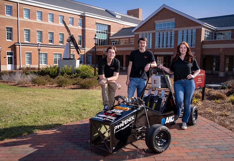 Student pose behind Formula 1 car they designed and built