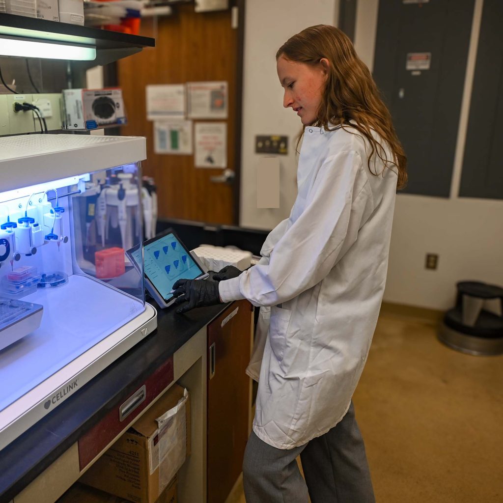 Elsa Eastment operates a BIO X6 bioprinter using a tablet in a laboratory.