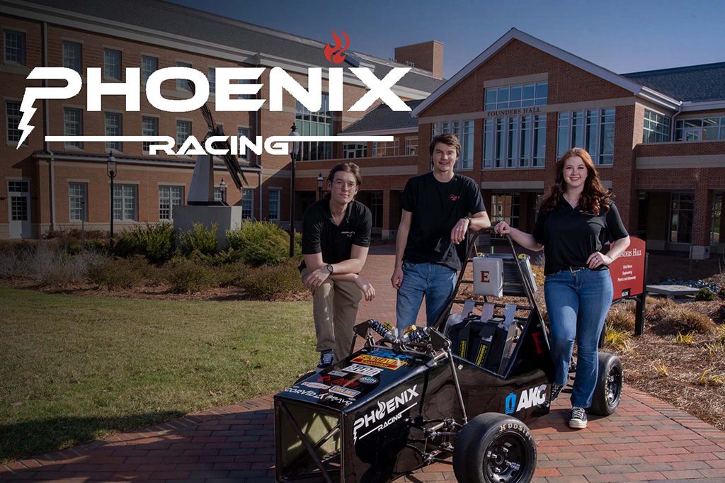 Student pose behind Formula 1 car they designed and built