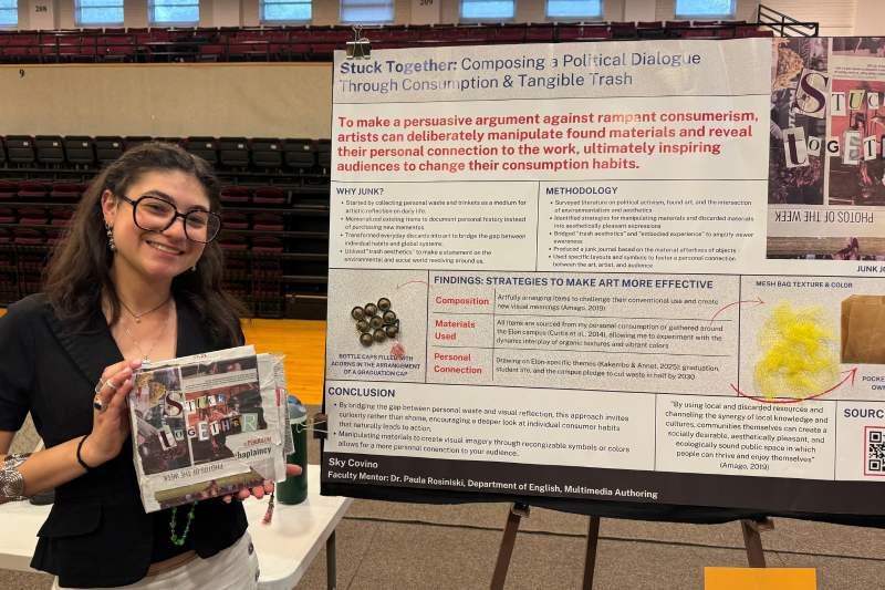 Student poses with project poster and art book
