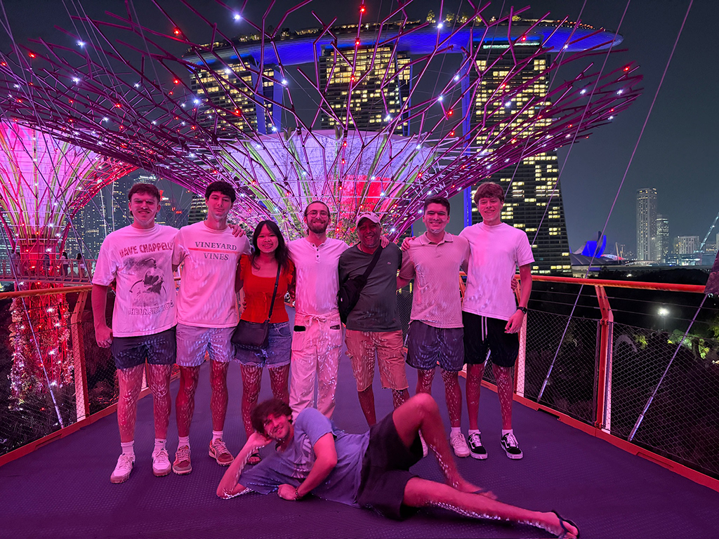 Elon students and faculty pose at Gardens by the Bay at night with Singapore’s skyline in the background
