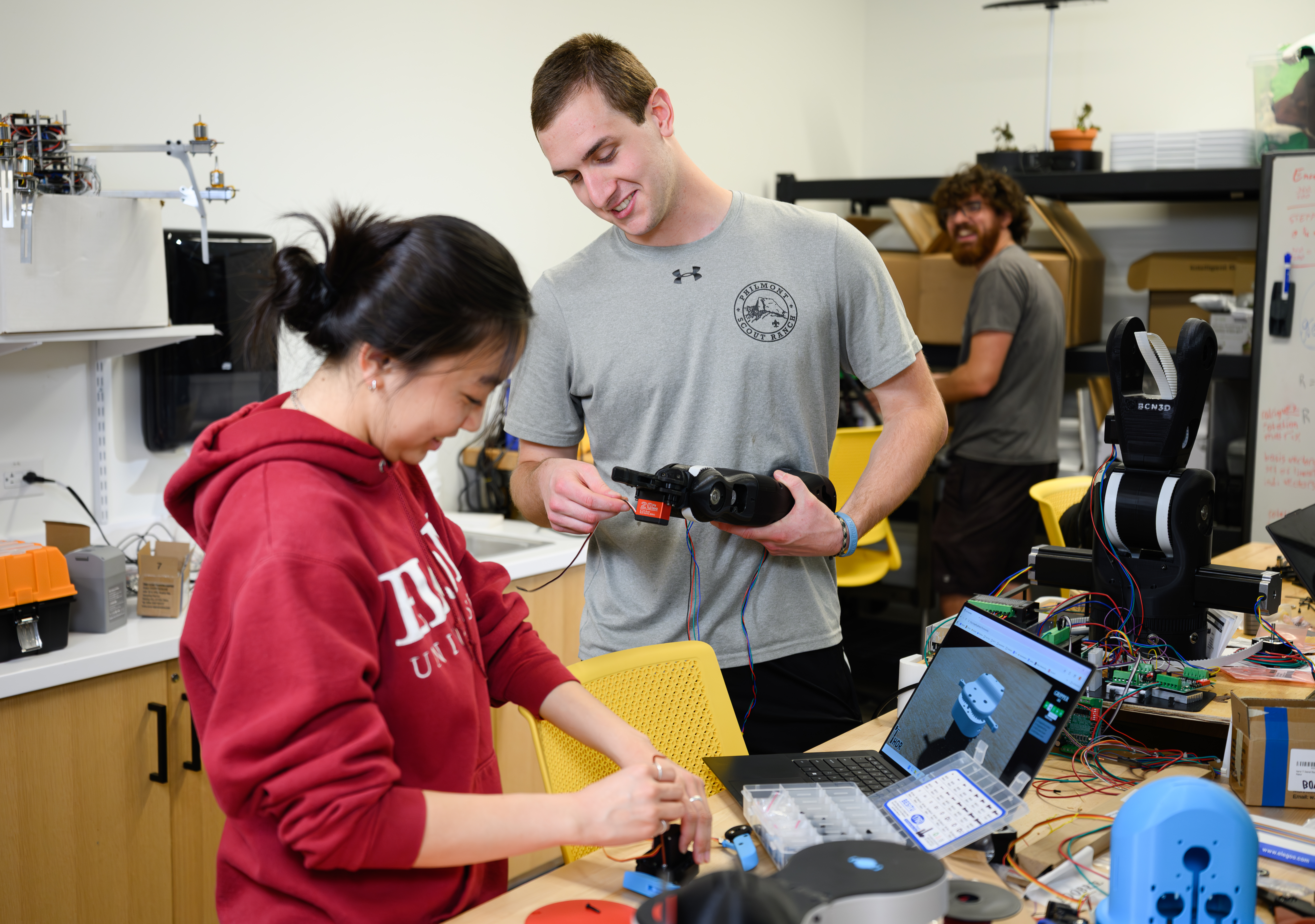 two students put together pieces of a robot during an engineering class