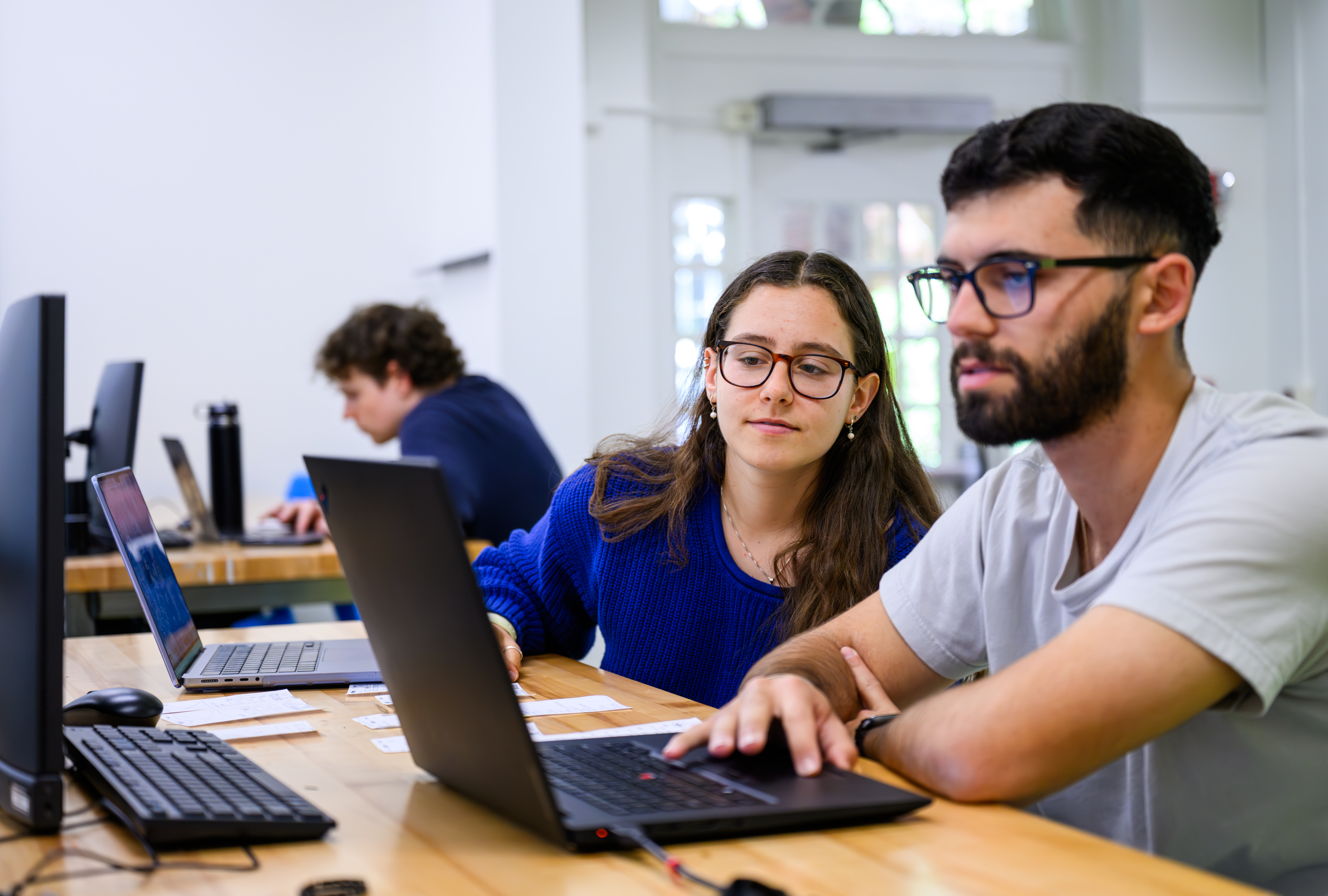two students look at a laptop during a computer engineering class