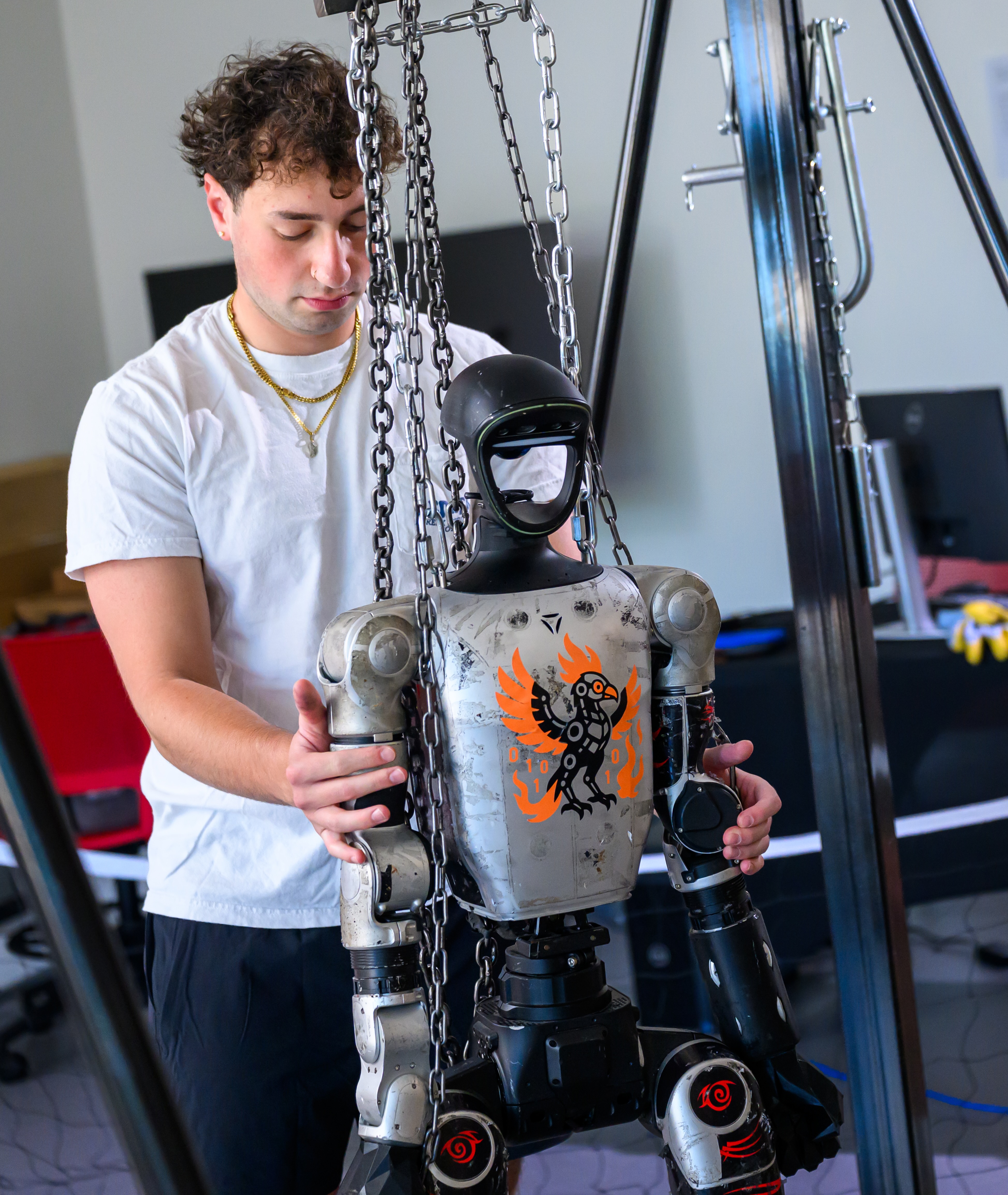 a student adjusts a humanoid robot during an engineering class
