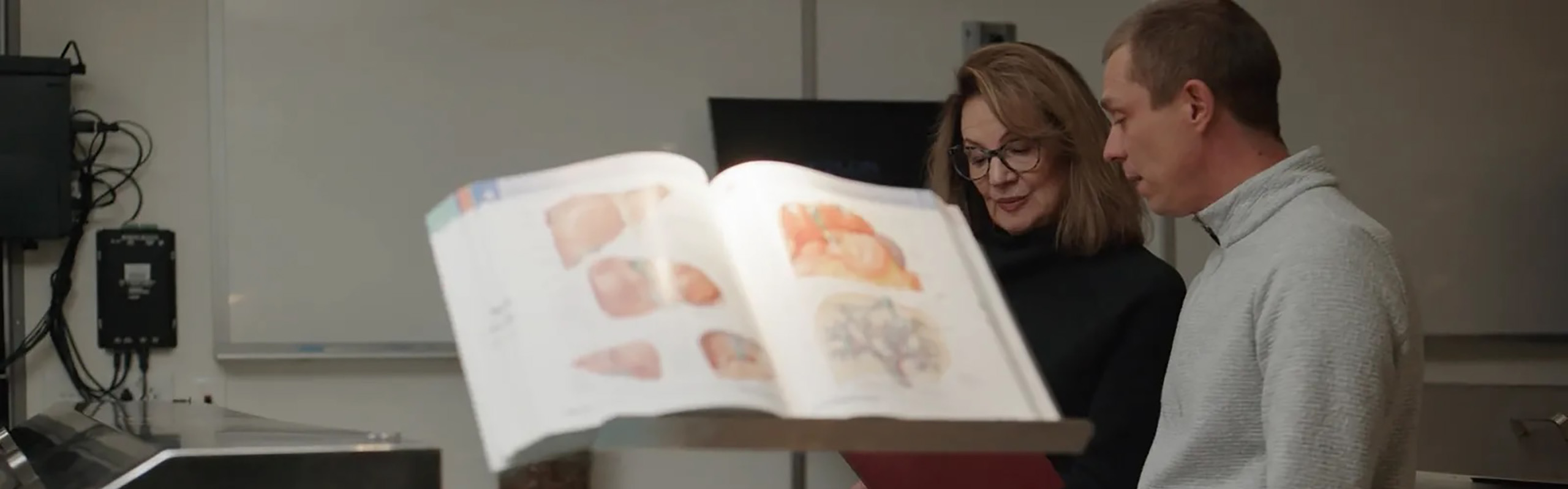 Instructors review detailed anatomical illustrations together in a teaching lab.