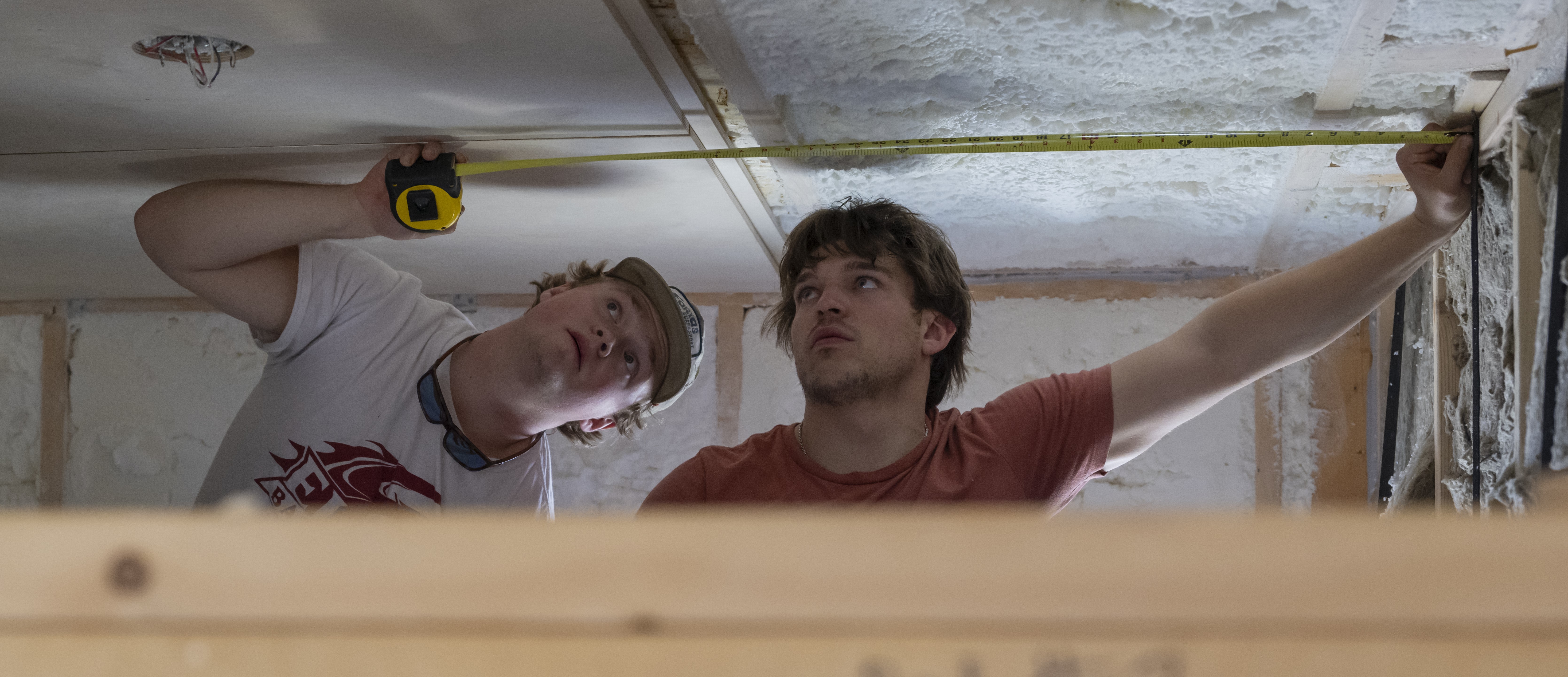 2 students measure ceiling panels in the student-built home in the EcoVillage at Loy Farm. Environmental science students have unique hands-on learning experiences at Elon.