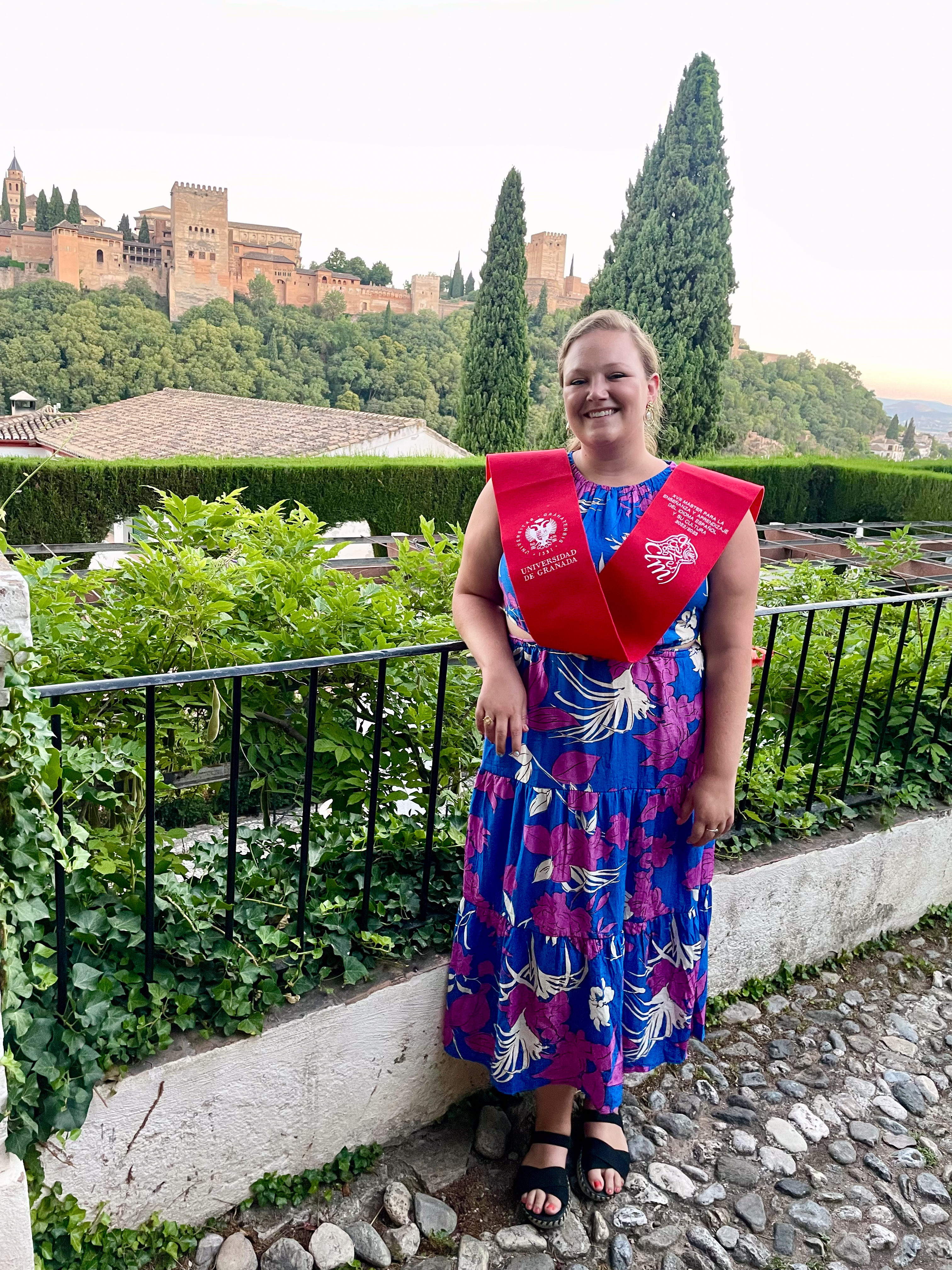 Erin Luther wearing a red sash and blue dress by a scenic overlook