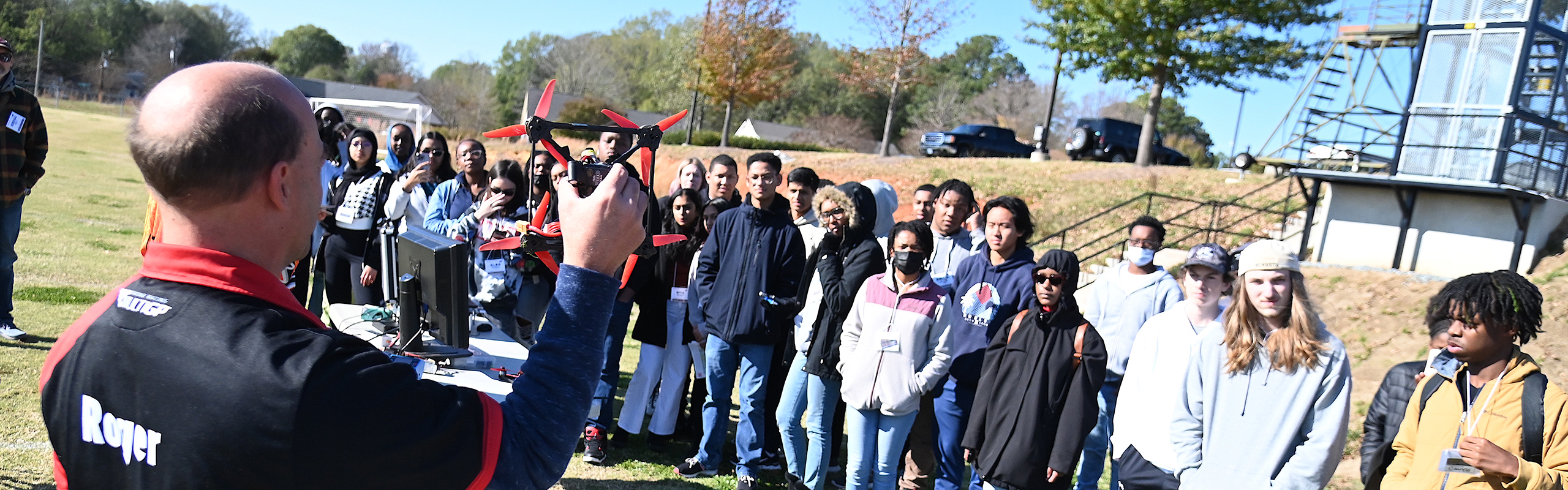 A group of high school students stand in a line during a drone flight demo.