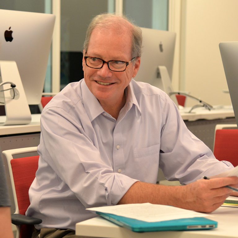 Glenn Scott sits at a desk in Dwight C. Schar Hall in Elon University's School of Communications.