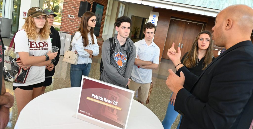 A group of Elon students listens to Elon alumnus Patrick Rees at a homecoming networking event.