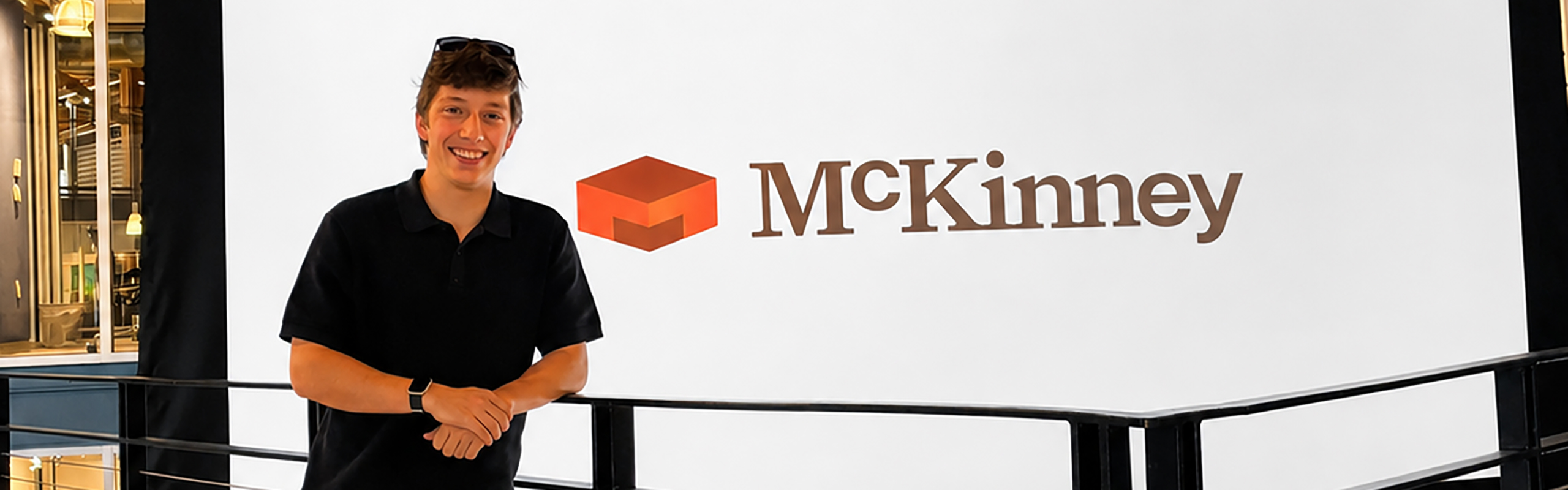 Elon student stands next to McKinney logo in the agency's building.