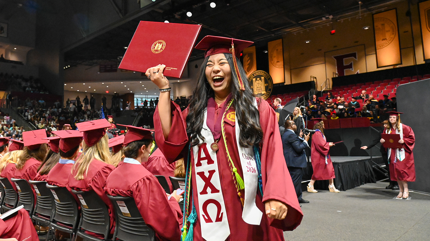 An Elon student holds up a diploma at graduation. 