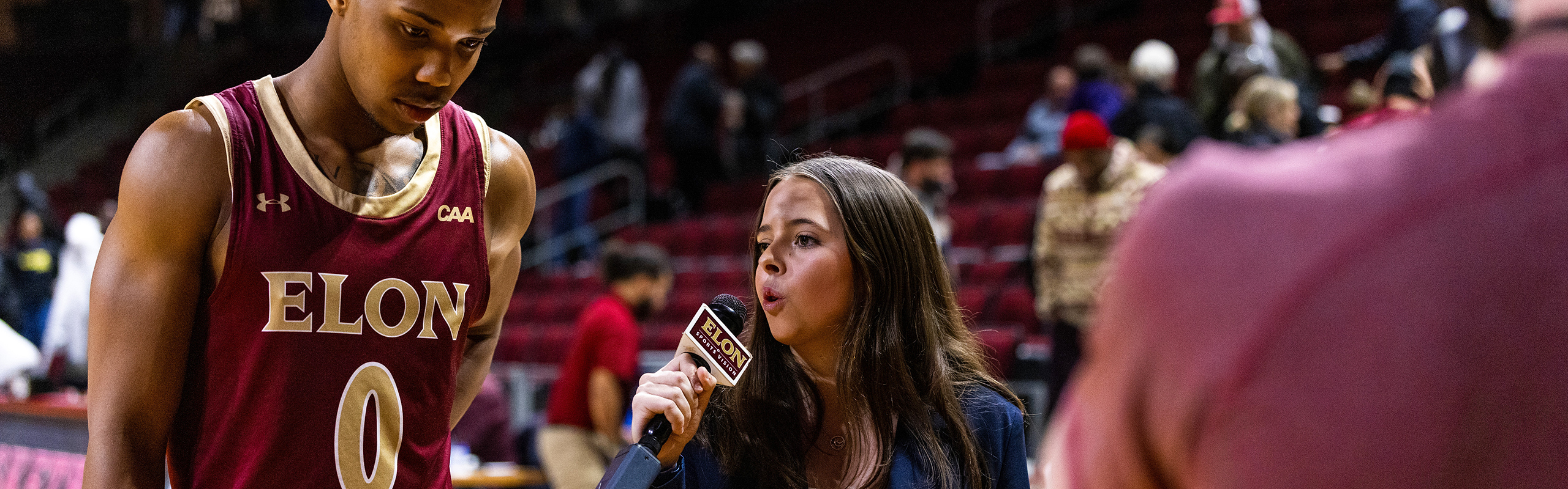 Rylee Marchand 28 holds microphone interviewing Elon basketball player.