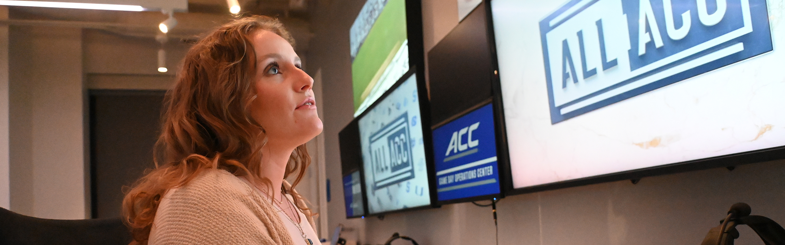 A young white woman sits at a row of computer monitors in the ACC Game Day Operations Center.
