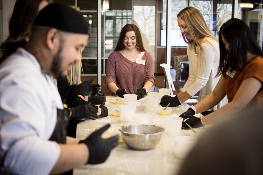 Elon Dining's Chef Danny stands in front of three students as they break down ingredients.