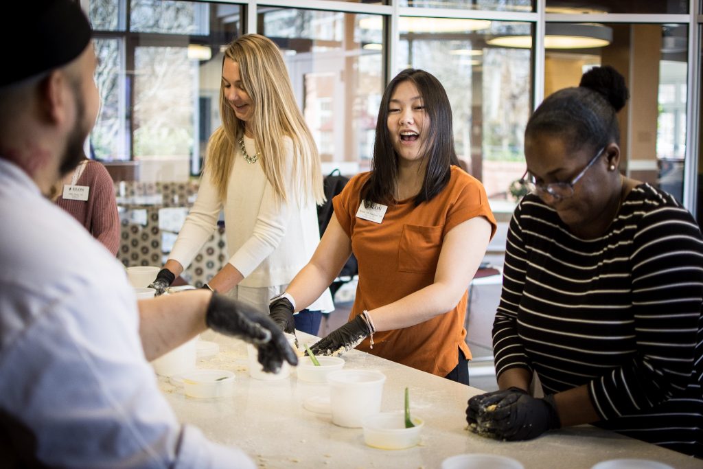 Elon Dining's Chef Danny stands in front of three students as they break down ingredients.