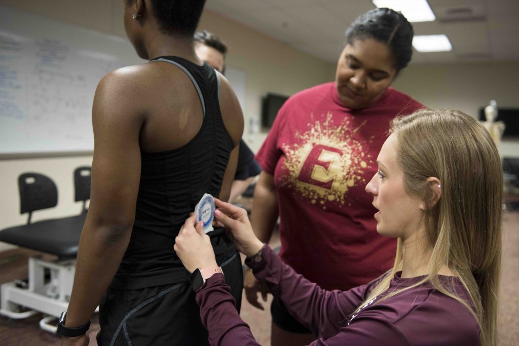 Melissa Scales works with DPT students Brianna Hurt, Jamila Wilson and Allison O’Halloran in a classroom simulation of muscle testing.